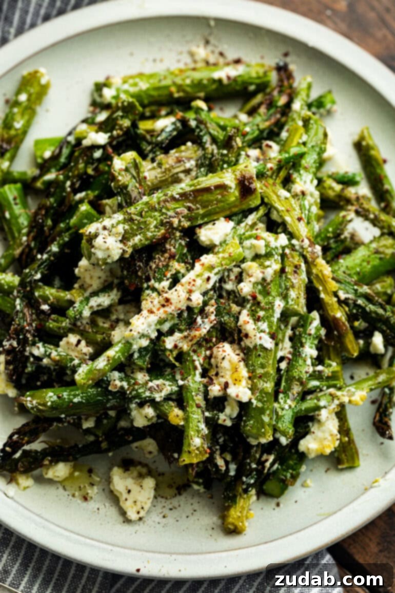 a photo of a pile of grilled asparagus spears tossed with feta cheese and sitting on a serving plate