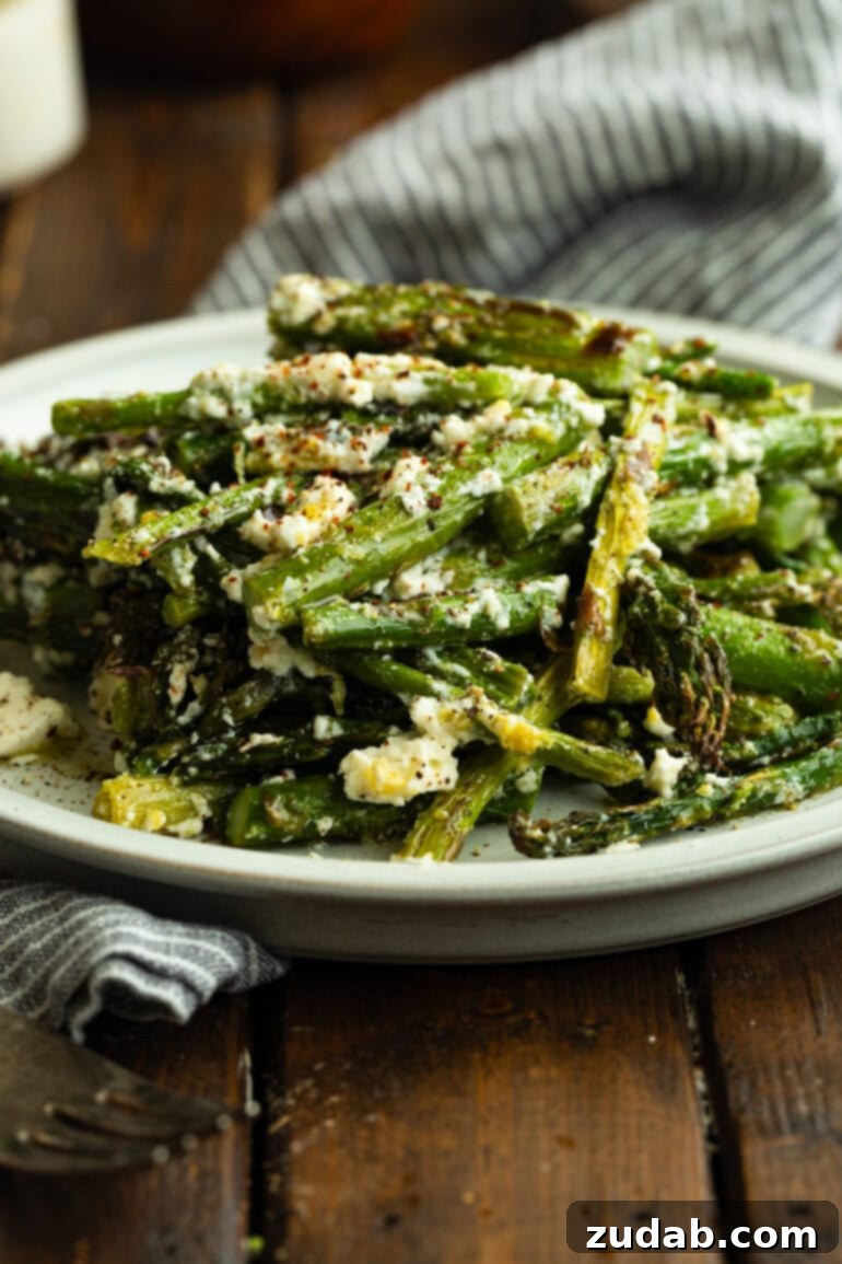 a photo of a serving plate full of grilled asparagus spears tossed with feta cheese and lemon zest