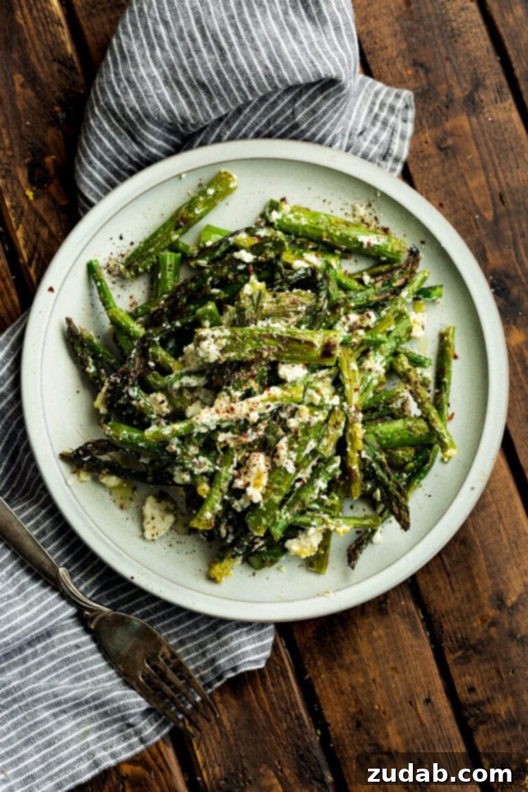 a photo taken over the top of a plate of grilled charred asparagus tossed with feta cheese and salt and pepper