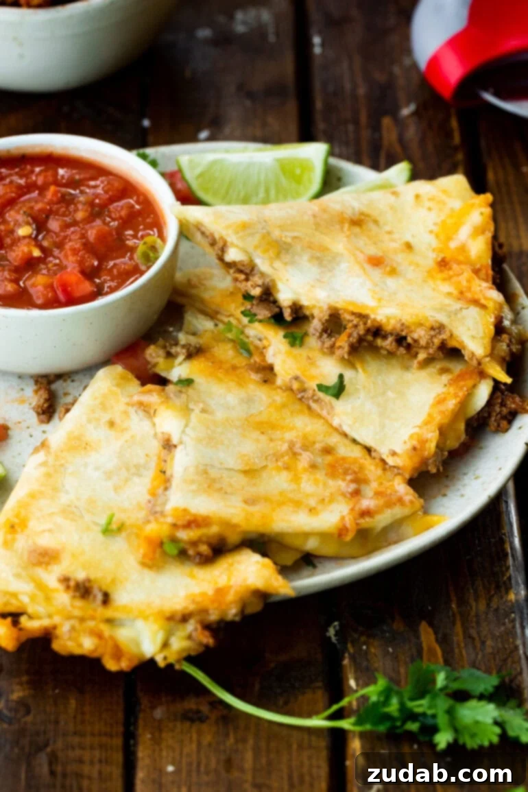 Unlocking Quesadilla Perfection 11 Several triangular segments of a golden, cheesy ground beef quesadilla, artfully arranged on a plate next to a small bowl of vibrant salsa, ready to be enjoyed.