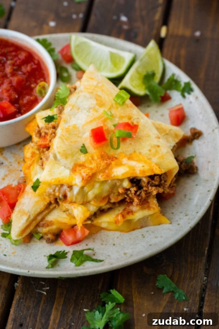 Unlocking Quesadilla Perfection 13 Several triangular segments of a ground beef quesadilla stacked on top of each other, showcasing the rich filling and golden, crispy exterior.