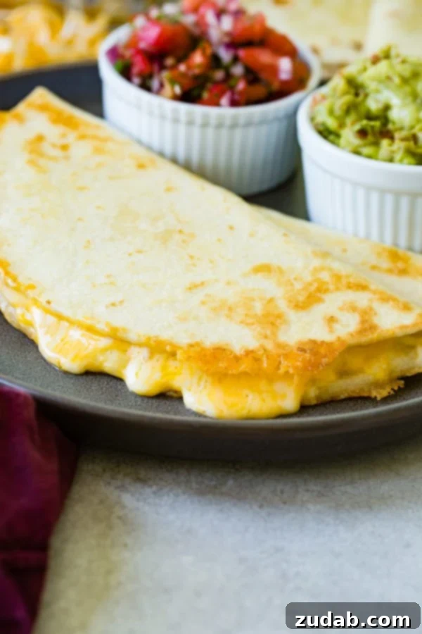 Secrets to the Best Quesadilla A beautifully presented cheese quesadilla on a plate, with a bowl of fresh pico de gallo and a bowl of creamy guacamole in the background, making a complete meal.
