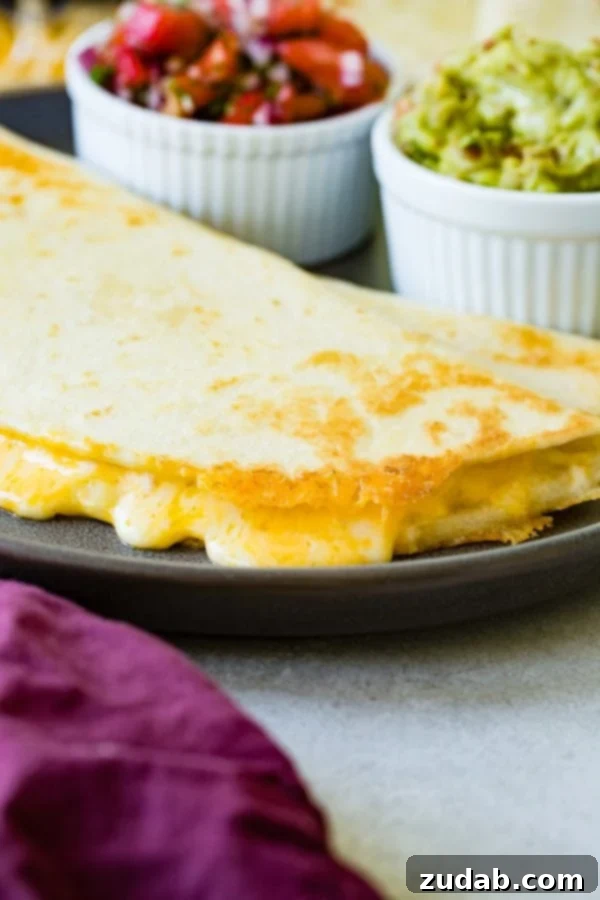 Secrets of the Best Quesadillas A close-up of a golden cheese quesadilla on a plate, with bowls of fresh pico de gallo and vibrant guacamole in the background, ready for dipping.