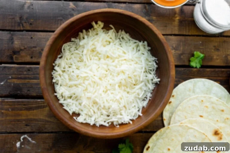 Unlocking Quesadilla Perfection 4 A large wooden bowl filled with freshly grated white Chihuahua cheese, illustrating the ideal texture and type of cheese for making delicious homemade quesadillas.