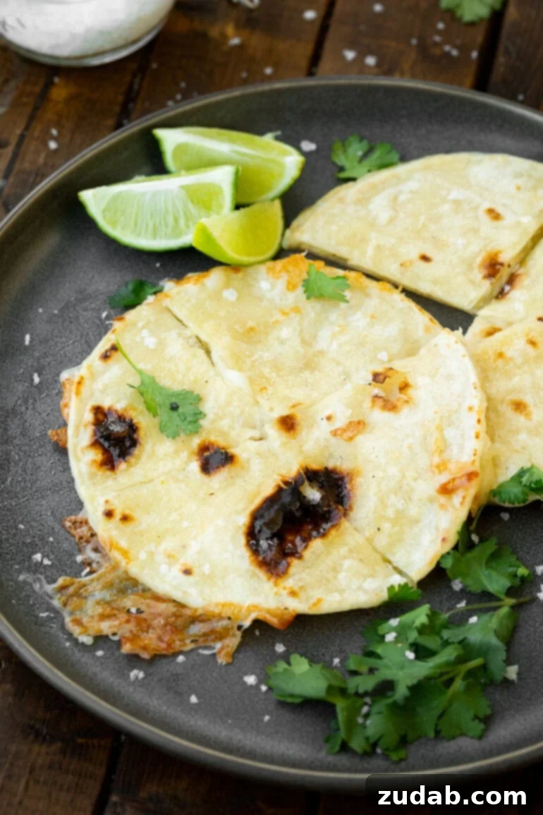 Unlocking Quesadilla Perfection 6 A golden-brown quesadilla served on a round wooden tray, garnished with fresh lime wedges and chopped cilantro, highlighting a beautifully presented and delicious meal.