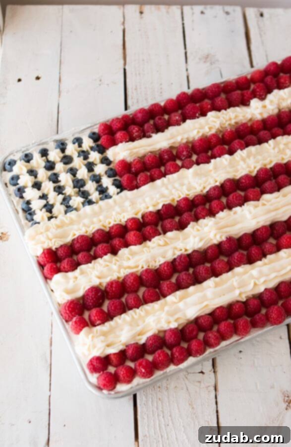 Experience the Best Flag Cake with its Unique Dual Frosting – Light Whipped Cream and Rich Buttercream! Flag Cake featuring a fluffy white cake base, topped with a delicate whipped cream frosting, fresh strawberries and blueberries, and intricate buttercream stripes. An ideal dessert for patriotic gatherings.