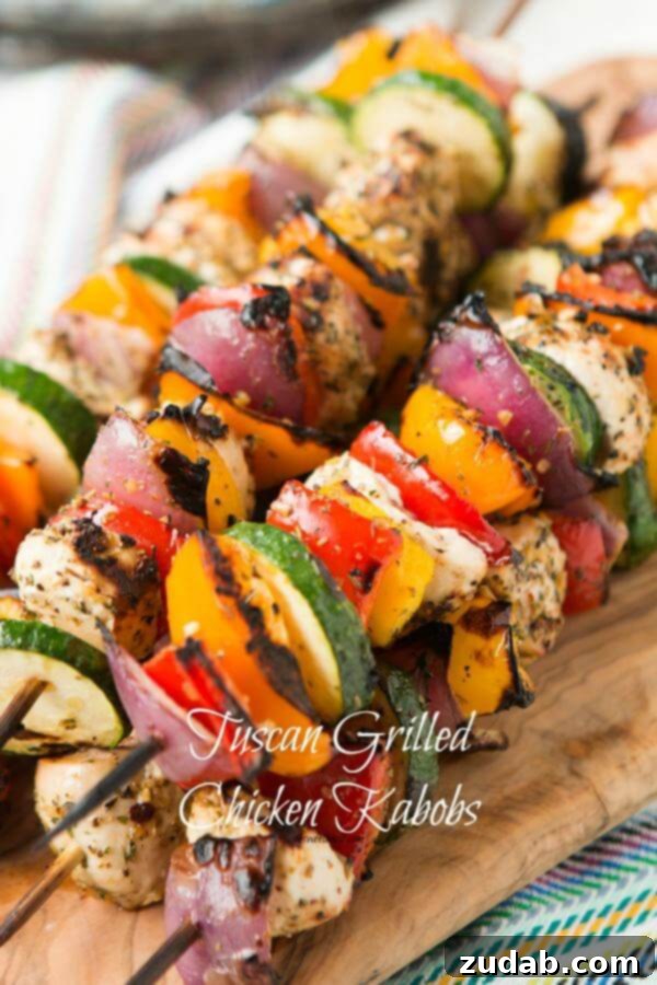 Fresh ingredients laid out for Tuscan chicken kabobs, including colorful bell peppers, zucchini, red onion, and marinated chicken pieces.