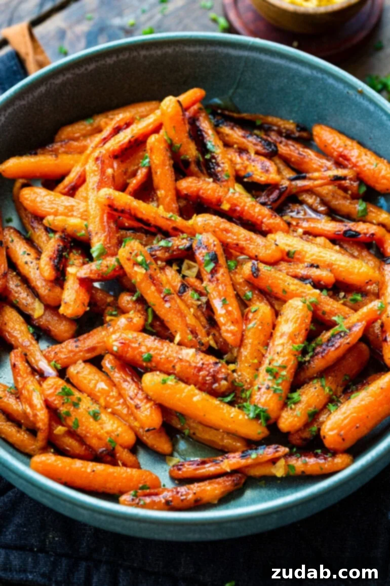 Golden Honey Garlic Roasted Carrots 2 A large blue serving bowl filled with golden honey garlic roasted baby carrots, generously sprinkled with chopped fresh herbs.