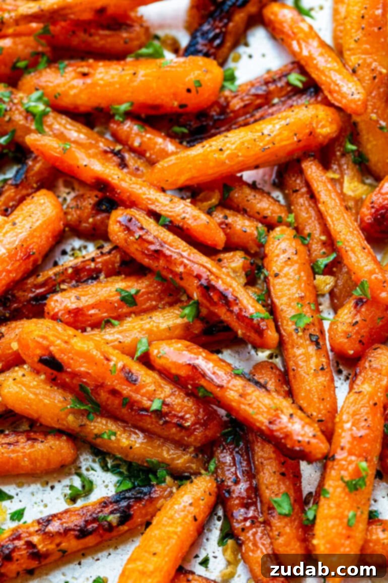 Golden Honey Garlic Roasted Carrots 3 A close-up photo of golden roasted baby carrots, beautifully glistening with glaze and sprinkled with minced fresh herbs.