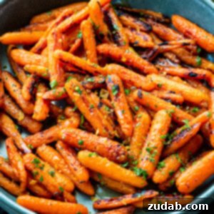 Golden Honey Garlic Roasted Carrots 8 A photo of a large blue serving bowl full of honey garlic roasted baby carrots sprinkled with chopped herbs
