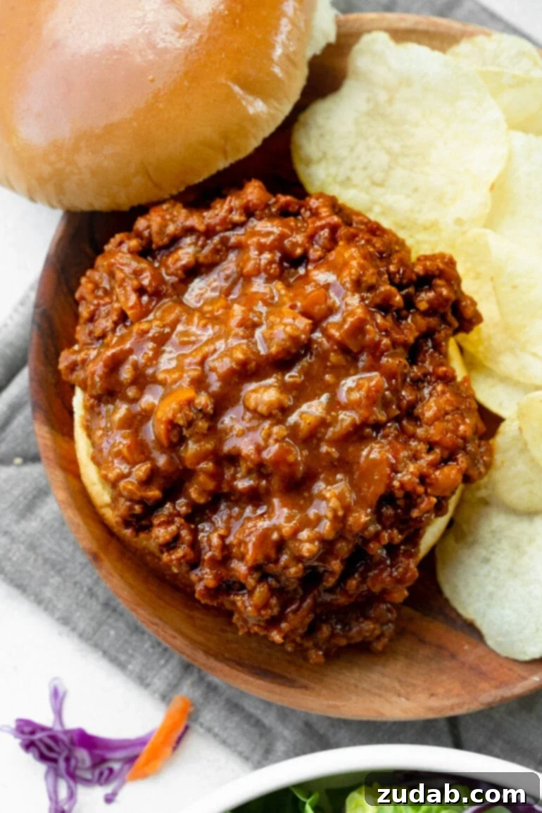 The Ultimate Sloppy Joe Recipe 6 An overhead view of a hearty sloppy joe sandwich with the top bun removed, revealing the generous, saucy ground beef filling, a perfect messy American classic.