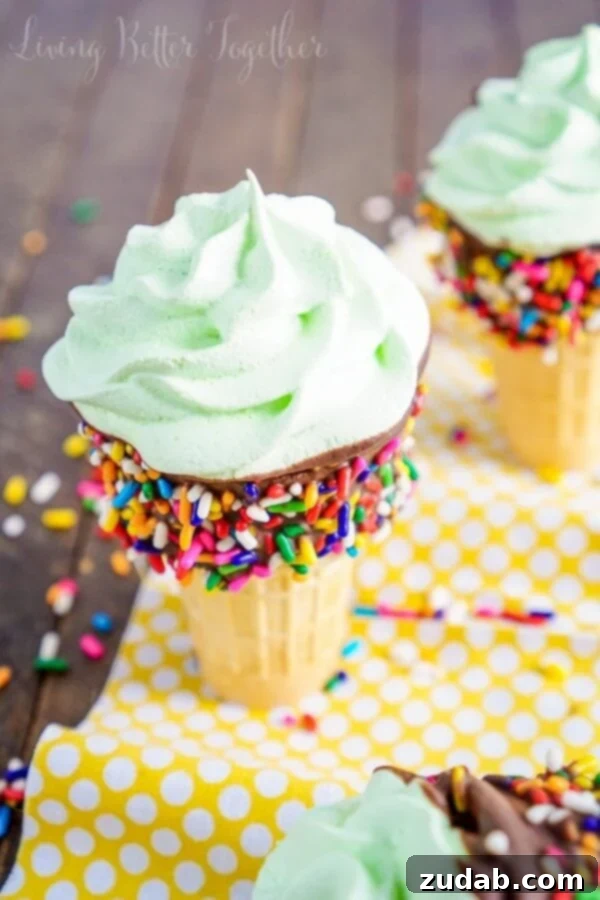 A hand holding a bright pink Meringue Ice Cream Cone, highlighting its perfect shape and colorful sprinkles.