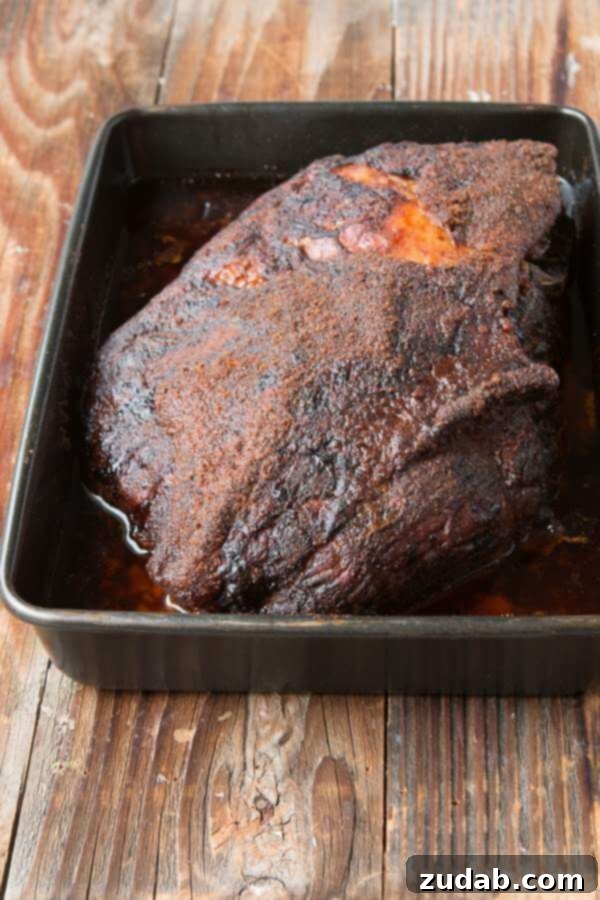 Want to make the best pulled pork from your own kitchen? This recipe for the world's best Carolina pulled pork all starts with a brine. a whole pork shoulder covered in a dry rub and sitting in a roasting pan full of juices ready for the oven