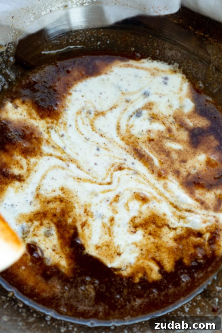 The Ultimate Homemade Apple Crisp 5 A stream of heavy cream gracefully pouring into a rich, dark brown syrup, illustrating a key step in creating the luscious apple crisp filling.