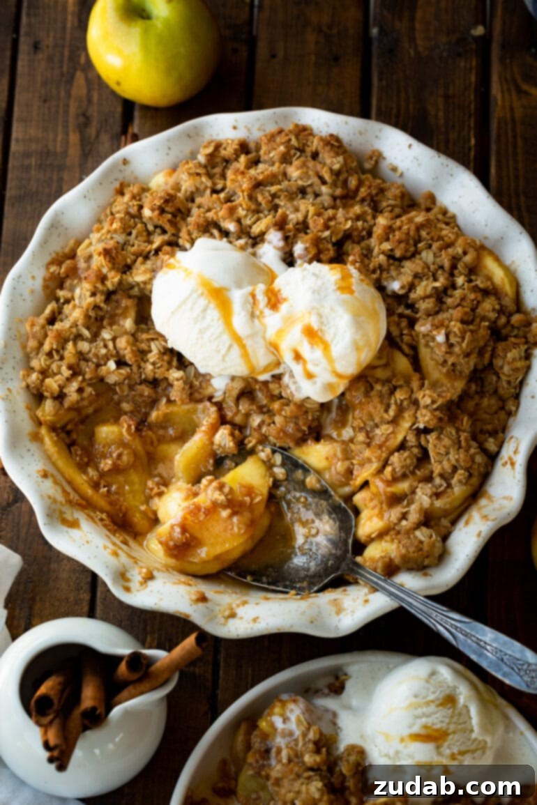 The Ultimate Homemade Apple Crisp 9 A large serving spoon gracefully scooping out a generous portion of warm, homemade apple crisp, revealing the tender, spiced apples beneath the golden, crunchy topping, accompanied by melting scoops of vanilla ice cream. This inviting scene epitomizes the perfect fall dessert.