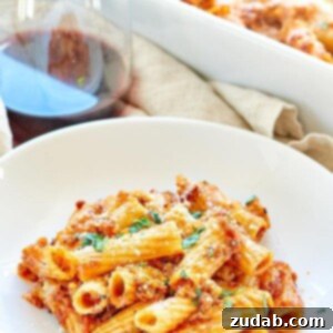 Zesty Sausage Rigatoni 2 Final baked Spicy Sausage Rigatoni, a close-up showing the rich, bubbly cheese and vibrant basil garnish, ready to serve as a comforting meal.