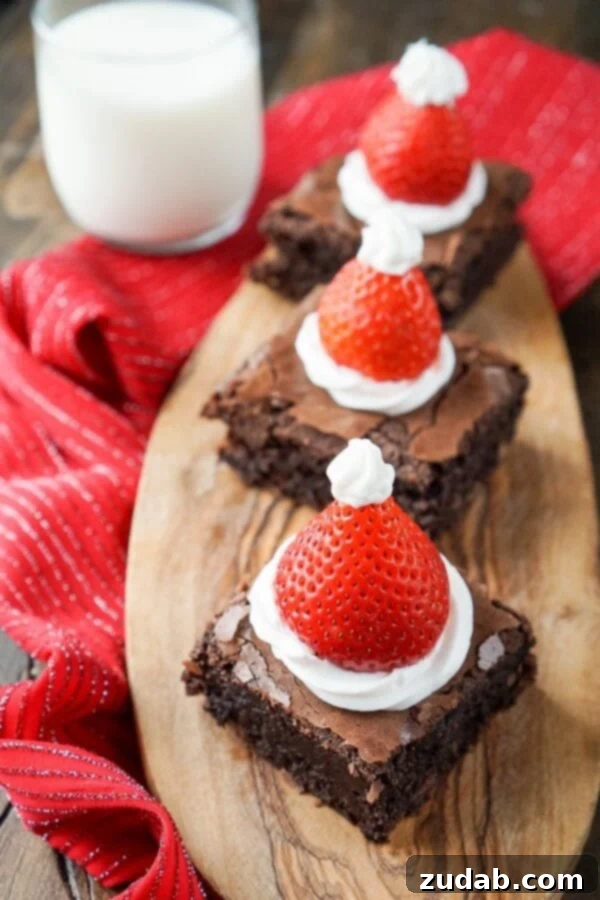 Holiday Brownie Recipe with Strawberries and Frosting Close-up of Santa Hat Brownies, highlighting the fresh strawberries and creamy frosting on rich chocolate.
