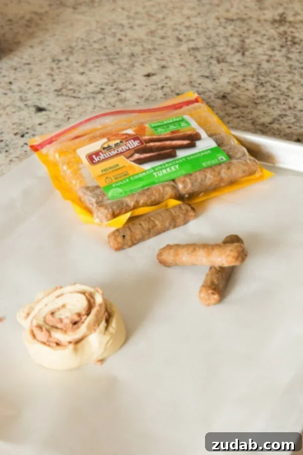 Oh, mama! We made these cinnamon roll pigs in a blanket dunkers for breakfast the other day and it's our new go to breakfast! A close-up shot of a single cinnamon roll pig in a blanket, golden brown and glistening, with a hint of vanilla drizzle. The focus is on the delicious texture, inviting viewers to imagine its taste. ohsweetbasil.com