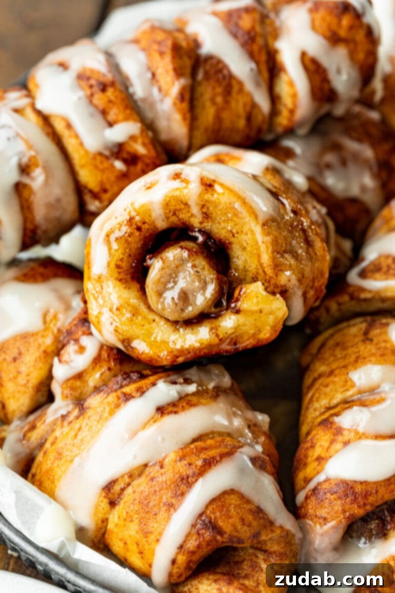 Pigs in a Sweet Blanket 8 A beautifully composed shot showing a cinnamon roll sausage dunker cut in half, revealing the warm, savory sausage inside, artfully arranged on top of several whole, perfectly baked dunkers. A testament to their deliciousness.