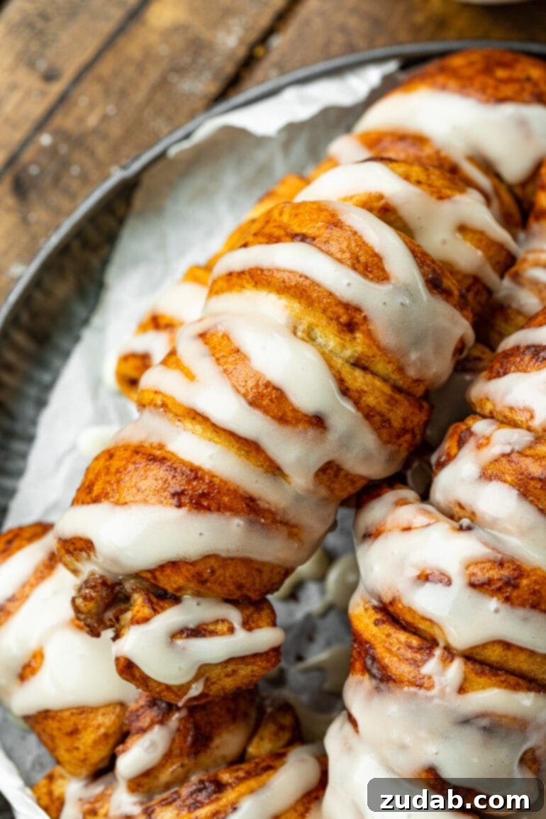 Pigs in a Sweet Blanket 9 An enticing photo of several freshly baked cinnamon roll pigs in a blanket, artfully arranged and generously topped with a delightful cream cheese drizzle, ready to be served as a scrumptious breakfast.