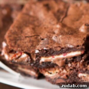 Candy Cane Crunch Brownies 3 Close-up of a sliced Ghirardelli Peppermint Bark Brownie, showing the melted peppermint layer inside