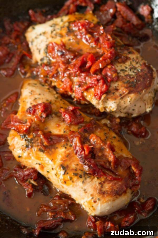 Simple marinated citrus Greek chicken with a two ingredient sauce. It's perfect all year round! A close-up of tender cooked Citrus Greek Chicken breasts, beautifully topped with sun-dried tomatoes and nestled in a rich, flavorful sauce.