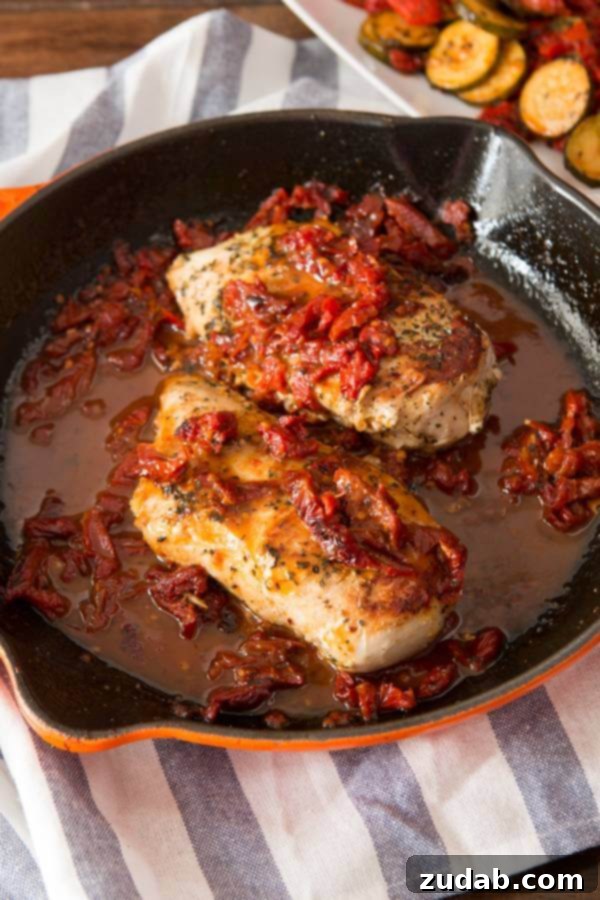 Simple marinated citrus Greek chicken with a two ingredient sauce. It's perfect all year round! Two succulent Citrus Greek Chicken breasts, crowned with sun-dried tomatoes and drenched in a simple, vibrant sauce, simmering beautifully in a cast iron skillet.