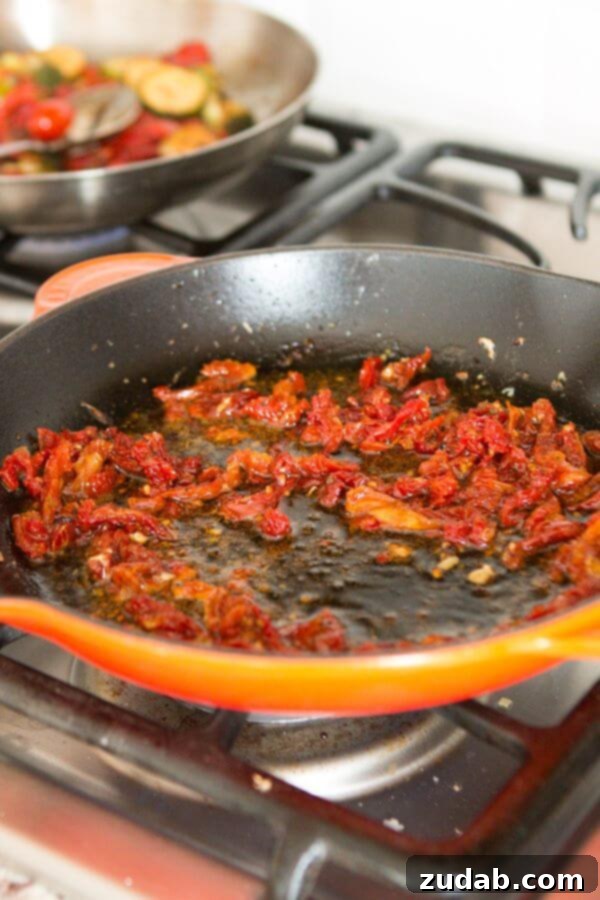 Simple marinated citrus Greek chicken with a two ingredient sauce. It's perfect all year round! A tantalizing close-up of vibrant sun-dried tomatoes simmering in zesty orange juice within a rustic cast iron skillet, forming the base of a delicious sauce.