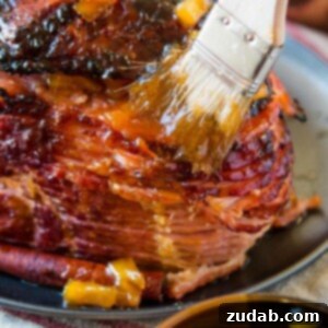 The Ultimate Brown Sugar Glazed Ham 3 Brushing sauce on a Brown Sugar Ham.