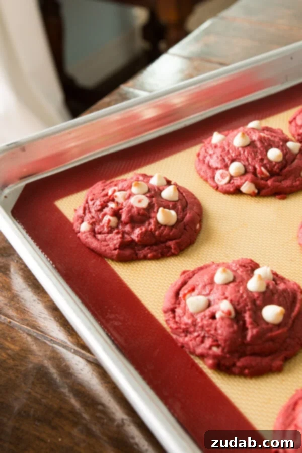 Red Velvet White Chocolate Chip Cookies, Oh Sweet Basil Close-up of freshly baked Red Velvet White Chocolate Chip Cookies, showcasing their deep red color and melted white chocolate chips.
