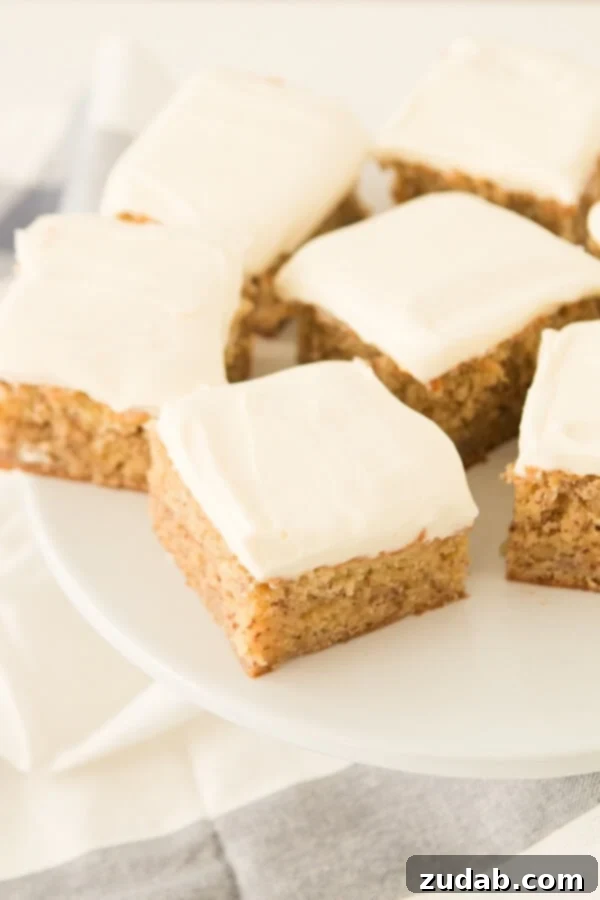 Indulgent close-up of thick, velvety cream cheese frosting generously spread on a fresh slice of banana cake.