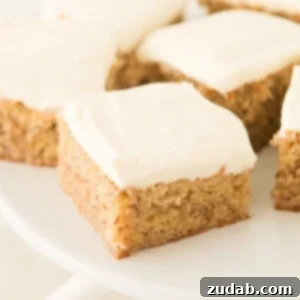 A beautifully decorated moist banana cake with creamy cream cheese frosting on a white platter.