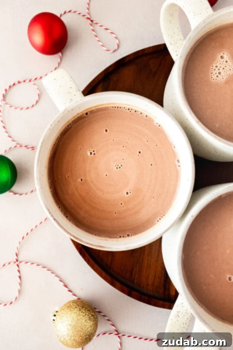 Blissful Homemade Hot Chocolate 4 An overhead shot of three pristine white mugs, each brimming with luscious, creamy homemade hot chocolate, ready to be enjoyed.