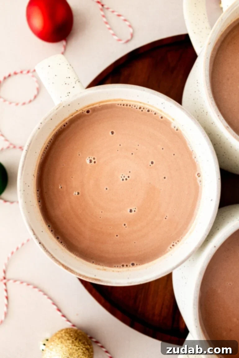Blissful Homemade Hot Chocolate 5 An inviting overhead view of three mugs filled with creamy homemade hot chocolate, perfectly garnished and ready for enjoyment.