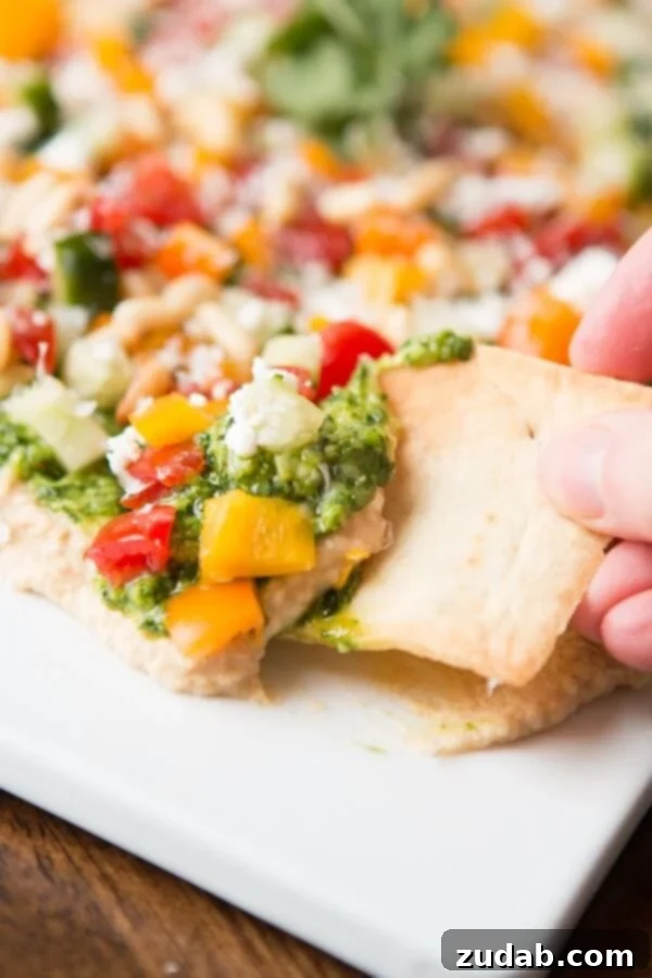 Easy Layered Hummus Dip for Parties Overhead view of the finished 8-Layer Hummus Dip with pita chips ready to serve