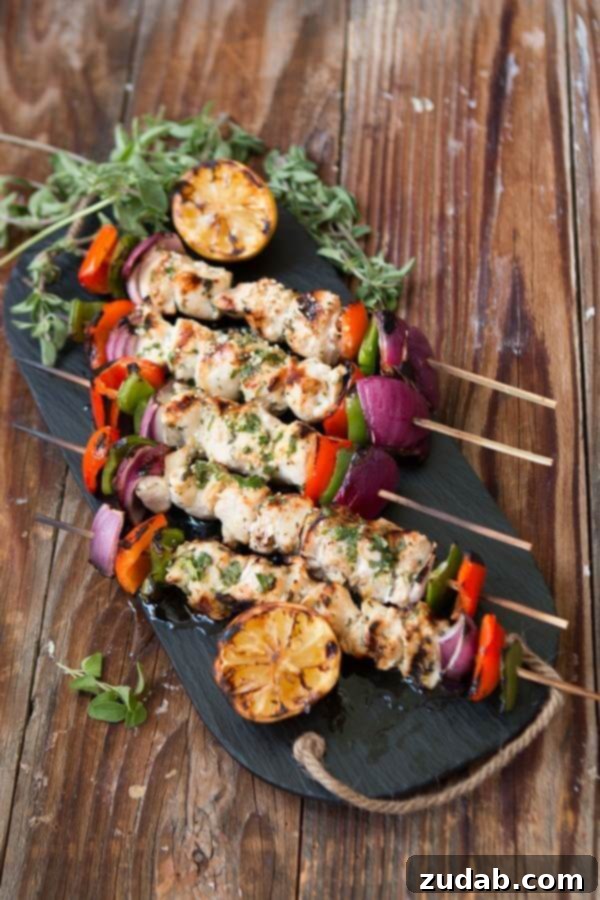 Looking for an easy and delicious chicken for the grill? Greek Chicken Souvlaki is full of flavor and turns out so moist! Five Greek souvlaki kabobs neatly arranged on a serving tray with grilled lemons.