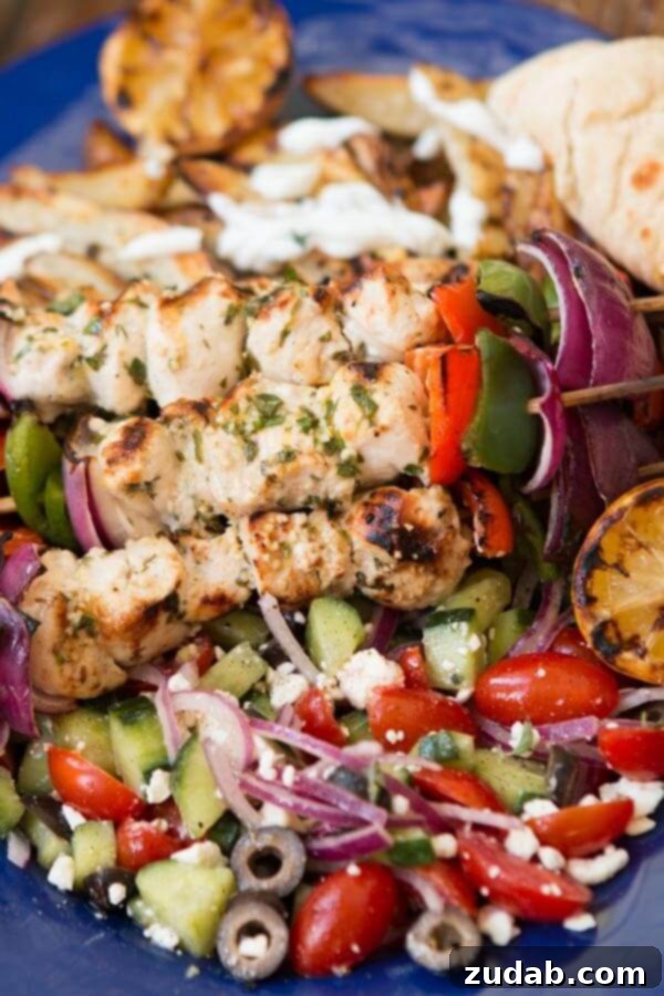 Looking for an easy and delicious chicken for the grill? Greek Chicken Souvlaki is full of flavor and turns out so moist! Chicken souvlaki kabobs resting on a bed of fresh Greek salad, ready to be served.
