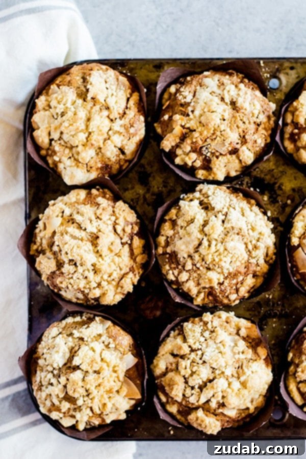 Golden Carrot Cake Muffins with a Generous Crumb Topping Close-up of a fluffy carrot cake muffin revealing its moist texture and golden crumb topping.