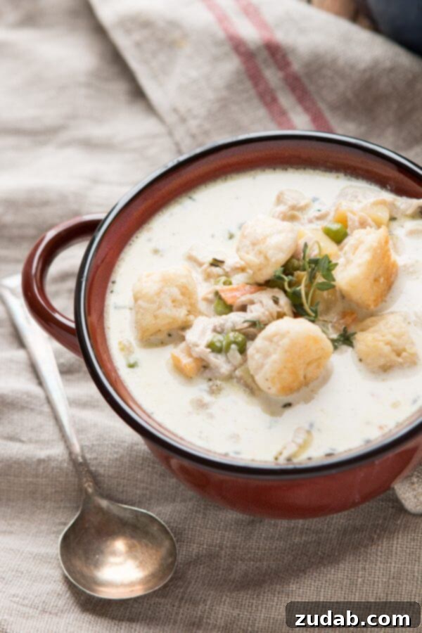 Velvety Chicken Pot Pie Soup 15 Close-up of the delicious texture and ingredients in a spoonful of pot pie soup with a biscuit.
