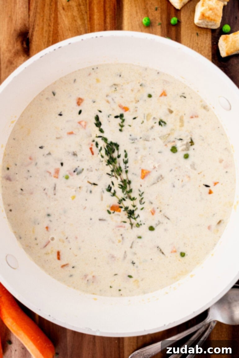 Velvety Chicken Pot Pie Soup 9 A large white bowl of creamy chicken pot pie soup sprinkled with fresh herbs, ready to be enjoyed on a chilly evening.