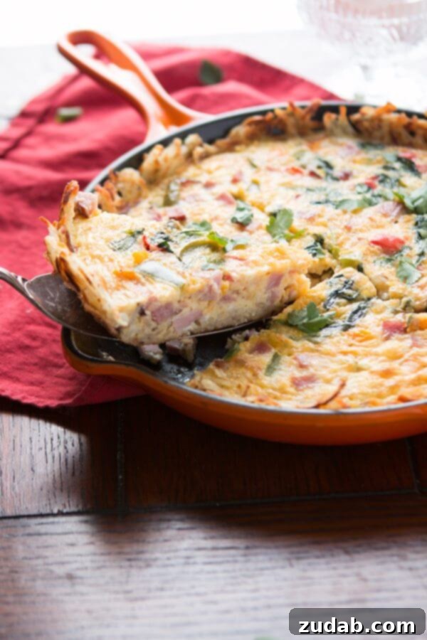 Golden hash browns make a great crust for this hash browns ham frittata! Serve as is or with hot sauce for a spicy little pop! low-carb Close-up shot of a fluffy hash browns ham frittata showing the egg and ham filling with cheese.