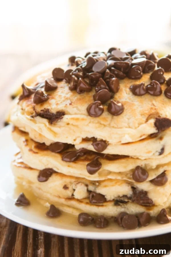 Better Than Mom's Chocolate Chip Pancakes Stack of fluffy homemade Chocolate Chip Pancakes on a white plate, ready to be served.