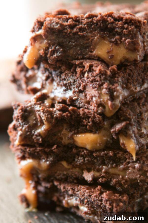 A thick stack of homemade caramel brownies with a rich, glistening caramel layer