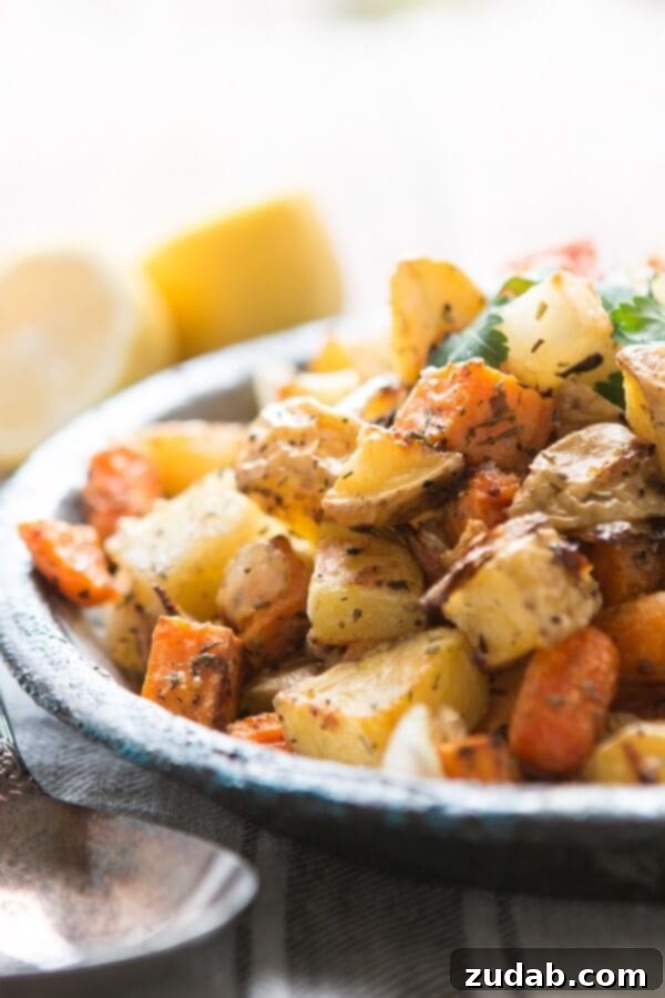Versatile Roasted Root Vegetable Medley: A Delicious Veggie Side Dish A large serving plate filled with roasted root vegetables, including zucchini, sweet potato, and broccoli, beside a fork, highlighting the variety and appeal of this veggie side dish.