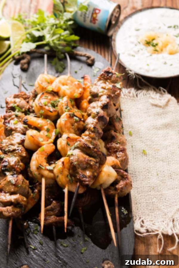 A close-up view of the perfectly grilled steak and shrimp on skewers, showing off their rich color and texture.