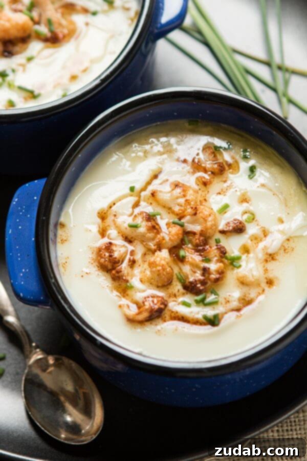A bowl of creamy brown butter cauliflower soup, garnished with browned florets and chives.