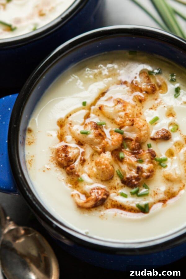 Close-up of brown butter cauliflower soup in a blue bowl, showing its creamy texture and garnish.
