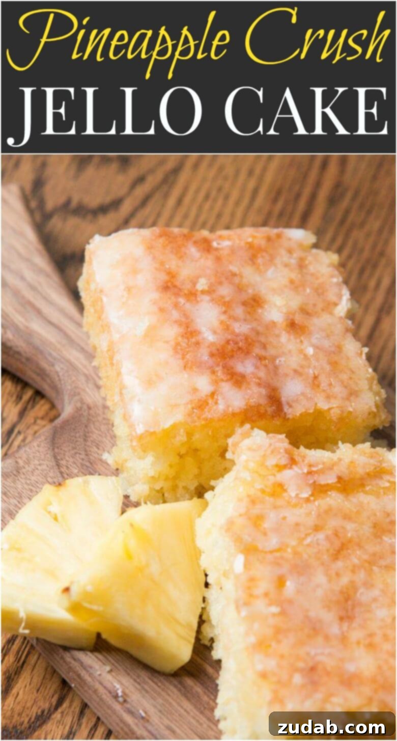 Pineapple crush jello cake is seriously one of the most moist cakes out there. The pineapple niblets are barely noticeable but give such flavor! A whole Island-Inspired Jello Pineapple Dessert with a Coconut Glaze on a pedestal, surrounded by fresh pineapple, ready to be sliced and served.