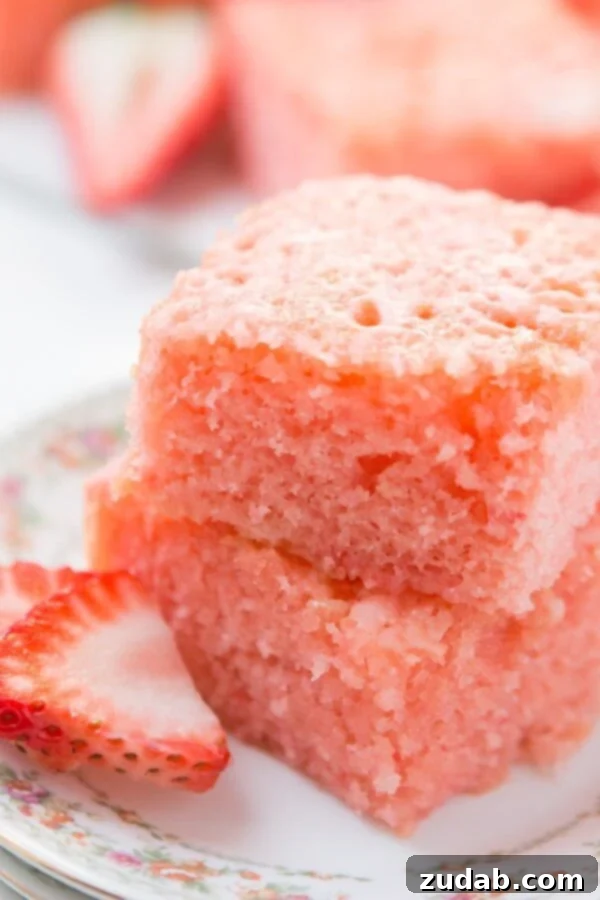 Tropical Pineapple Cloud Cake with Coconut Cream Glaze 2 A beautiful china plate showcases two slices of layered strawberry lemonade jello dessert, elegantly garnished with fresh strawberry slices for a delightful touch.
