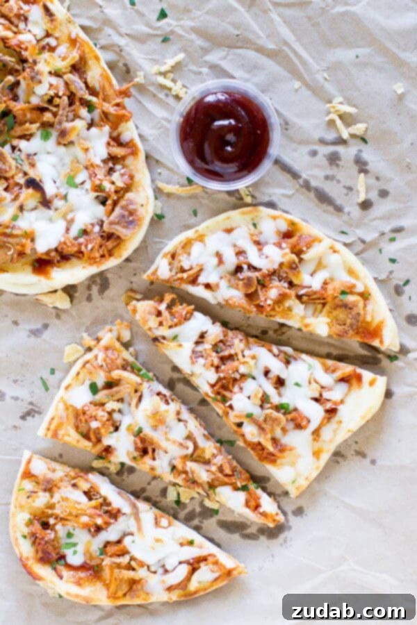 Easy Pulled Pork Pizza puts leftovers to work! Use a flatbread crust, barbecue sauce, cheese, and crunchy canned onions for a tasty dinner ready in 10 minutes! Four delicious pieces of Pulled Pork Pizza with a small cup of barbecue sauce.